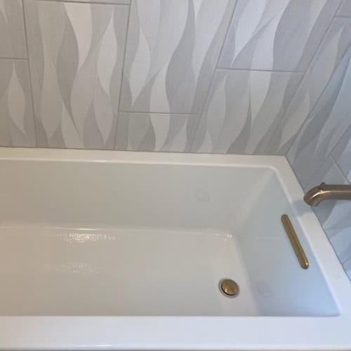 White Bathtub Renovation With Decorative Tile By Stag Homes Design Build In Kansas City Modern white bathtub with wave pattern wall tile in Kansas City bathroom renovation by Stag Homes Design Build