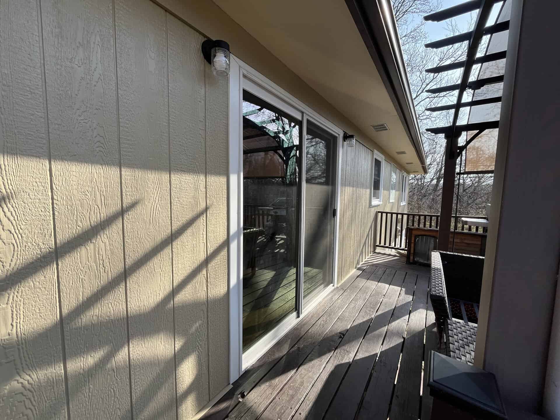 Pergola Deck Siding Siding installation contractor working on beige vertical panels beside wooden deck and pergola in kansas city
