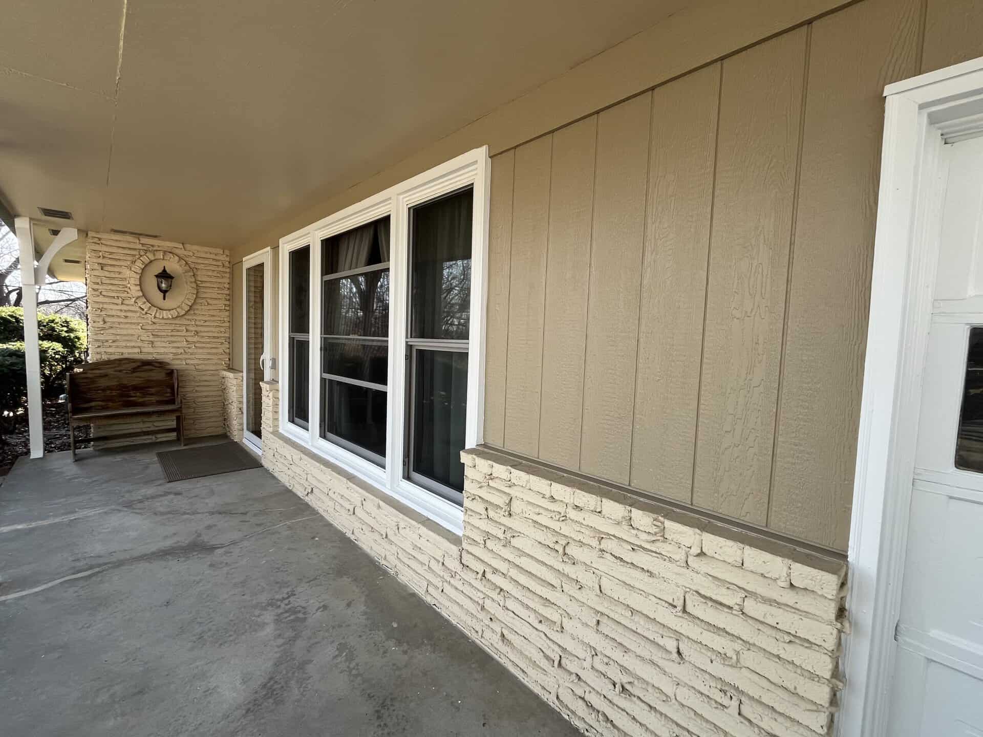Front Porch Siding Installation siding installation contractor showcasing tan vertical panels and cream brick exterior on a clean front porch with windows and glass door in kansas city