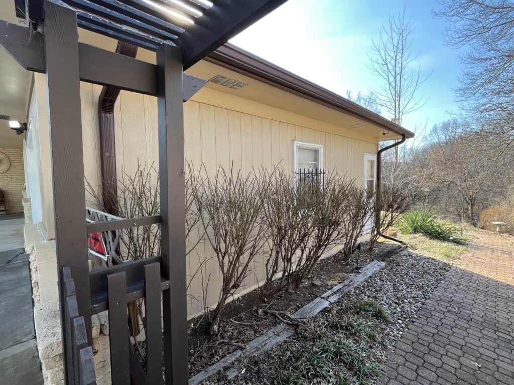 Side Wall Siding Siding installation contractor completing beige vertical siding along house wall with pergola and garden bed in kansas city